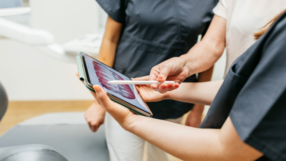 Três pessoas a olhar atentamente para um tablet